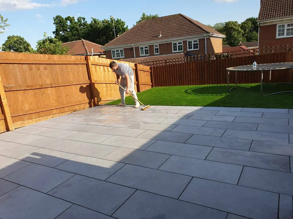 Large grey porcelain patio being cleaned beside a new lawn