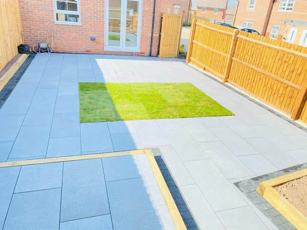 Grey porcelain patio with an inset lawn and gold trim strips