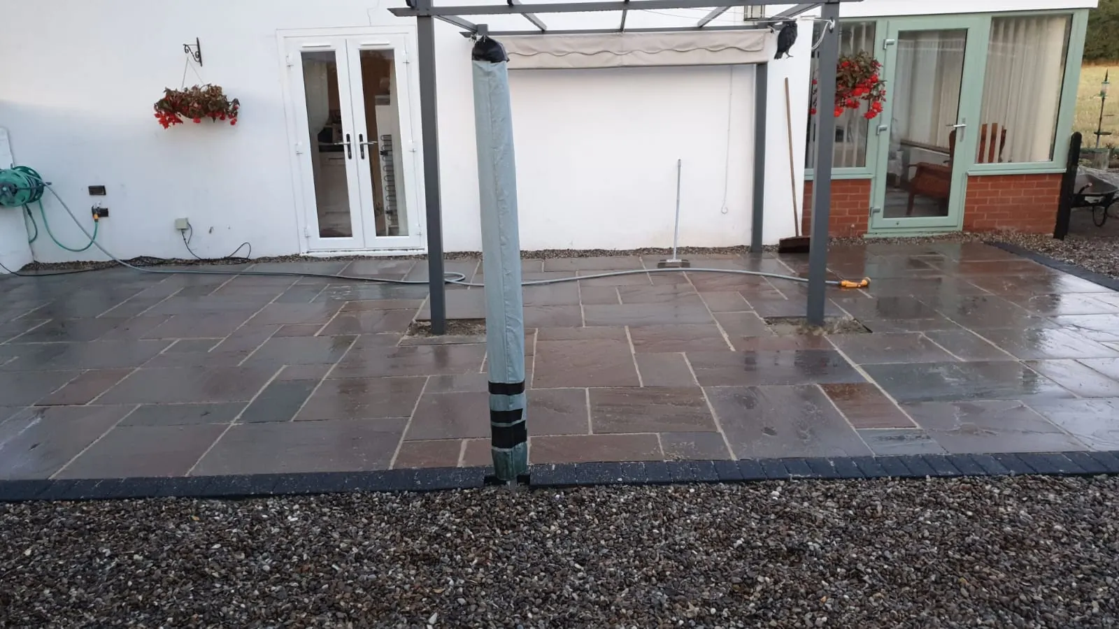 Grey porcelain patio under a pergola with a gravel border