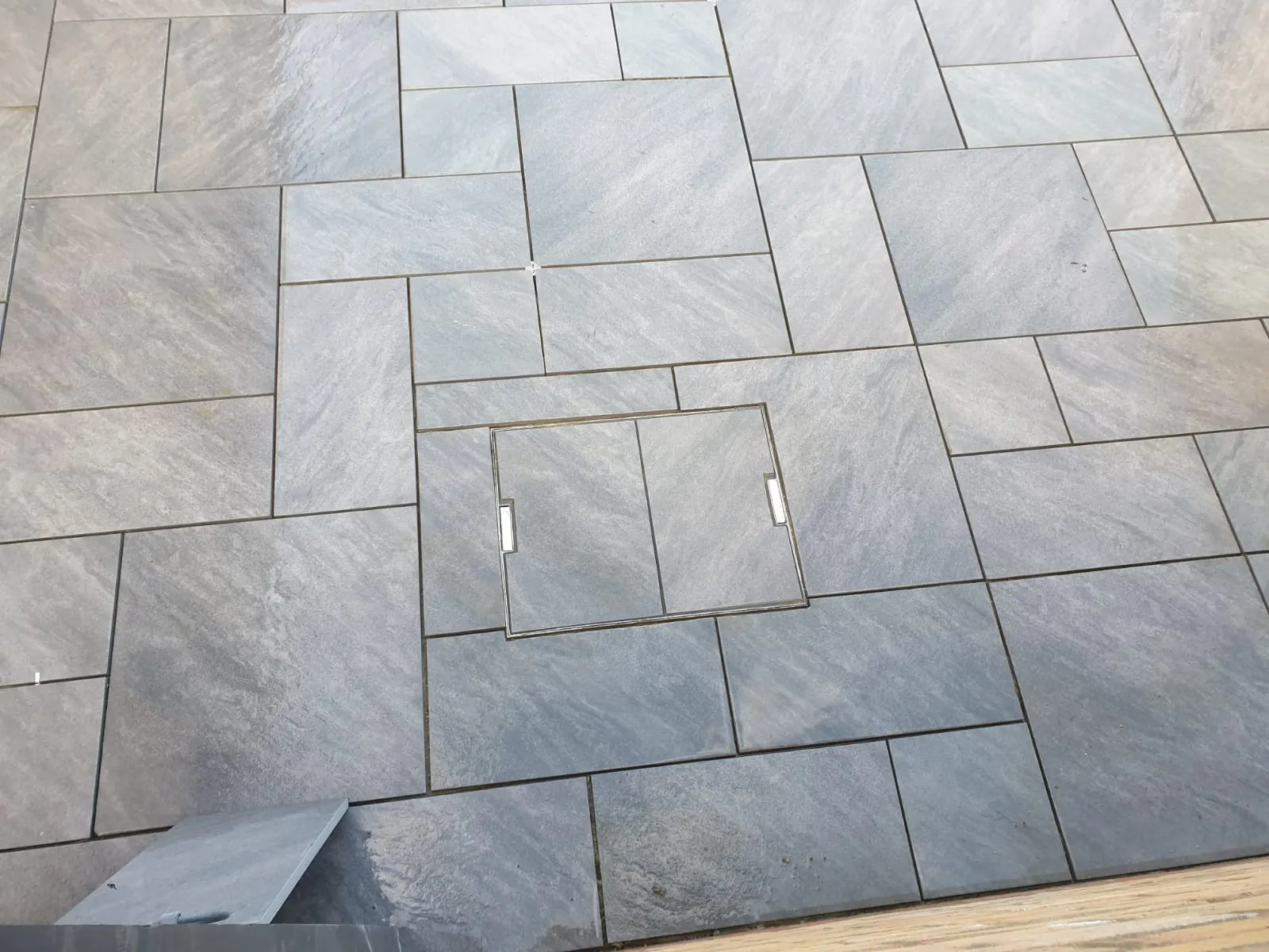 Grey porcelain patio with a recessed manhole cover