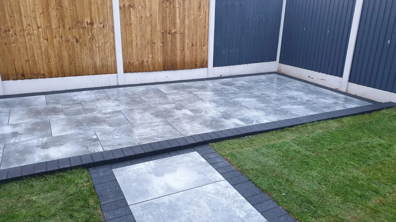 Grey porcelain patio and slab path beside a lawn