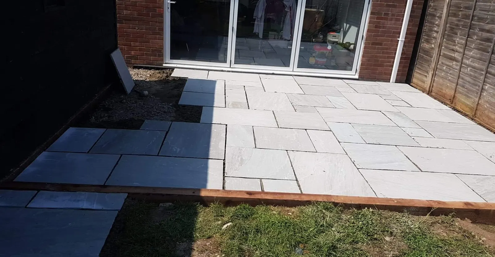 Grey porcelain patio outside sliding doors with a timber edge