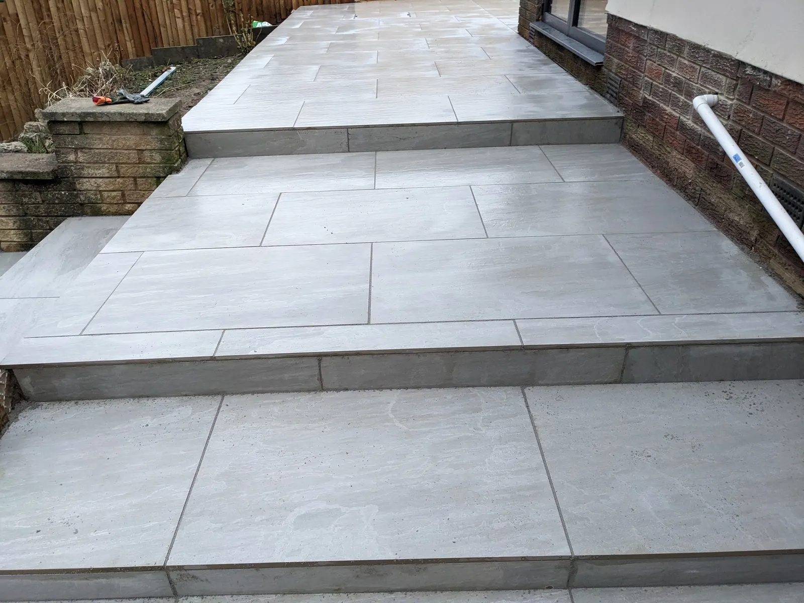 Grey porcelain patio steps down the side of a house