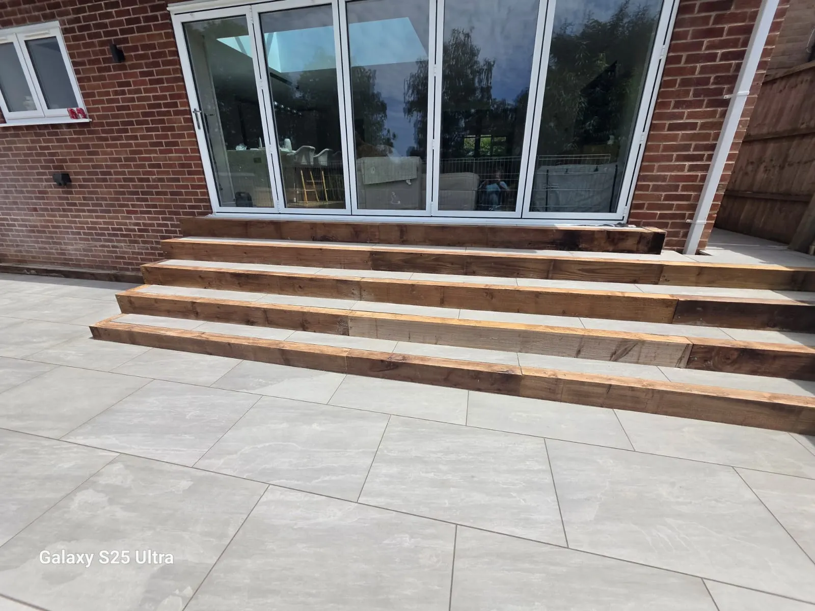 Grey porcelain patio with wide sleeper steps up to bifold doors