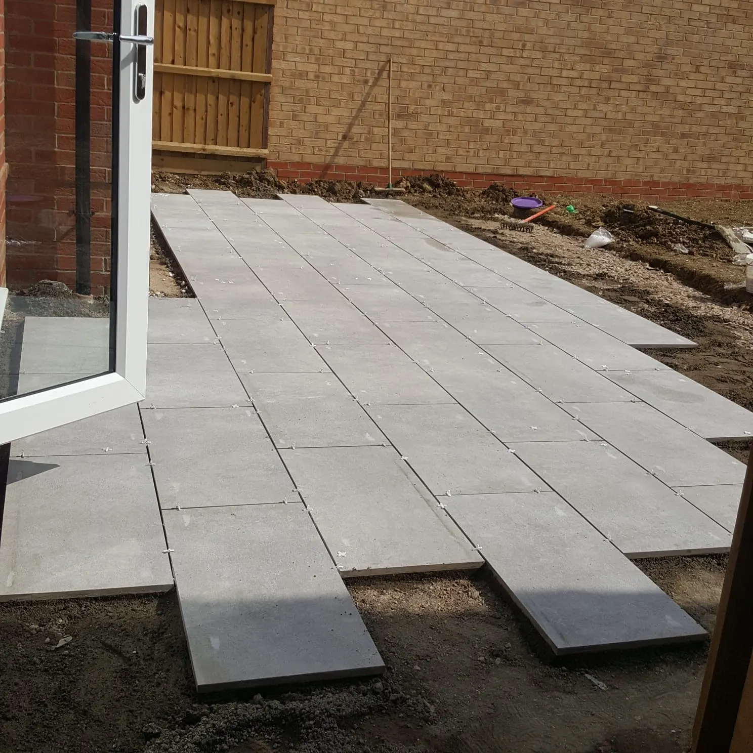Grey porcelain plank slabs being laid outside French doors