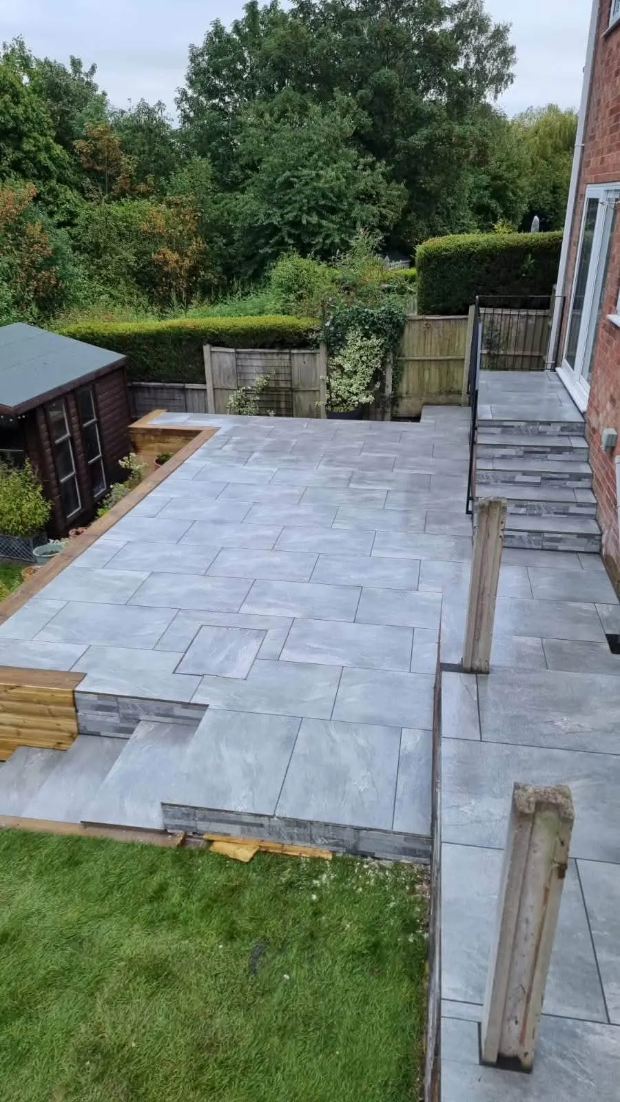 Grey porcelain patio terraced down a sloping garden with steps
