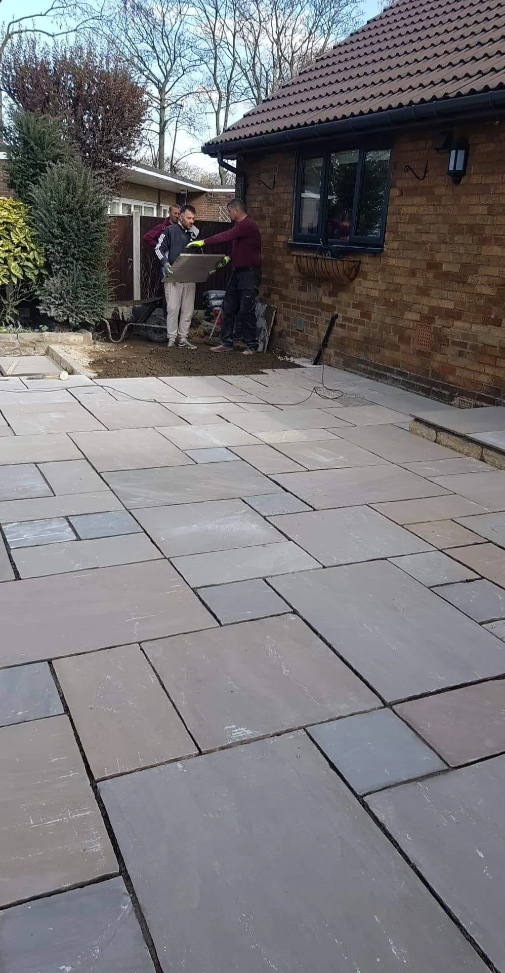Grey sandstone patio along the side of a bungalow