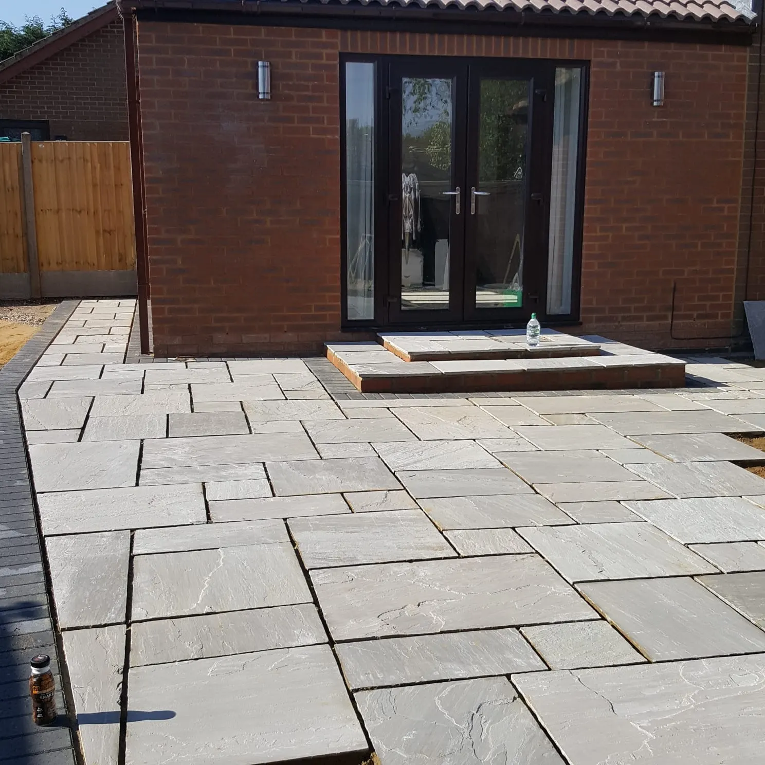 Grey sandstone patio up to a step at a garden room