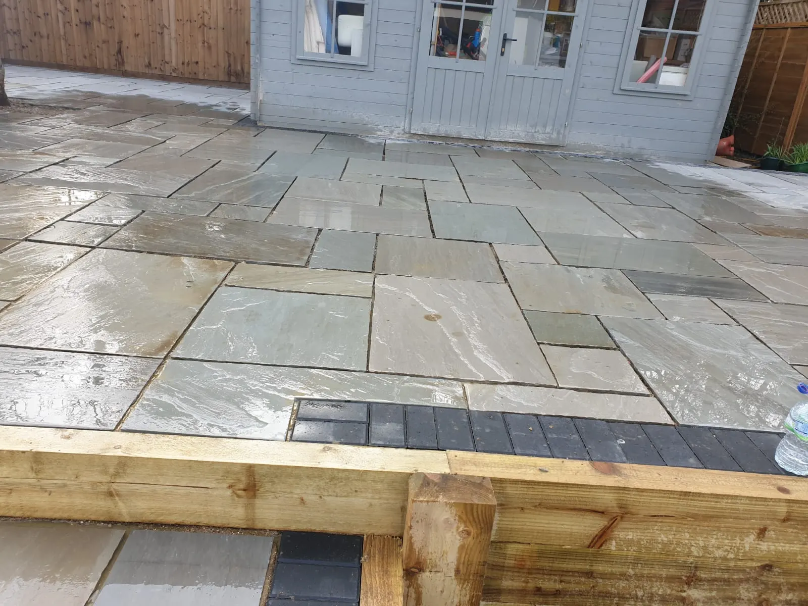 Grey sandstone patio with a sleeper step and a charcoal border