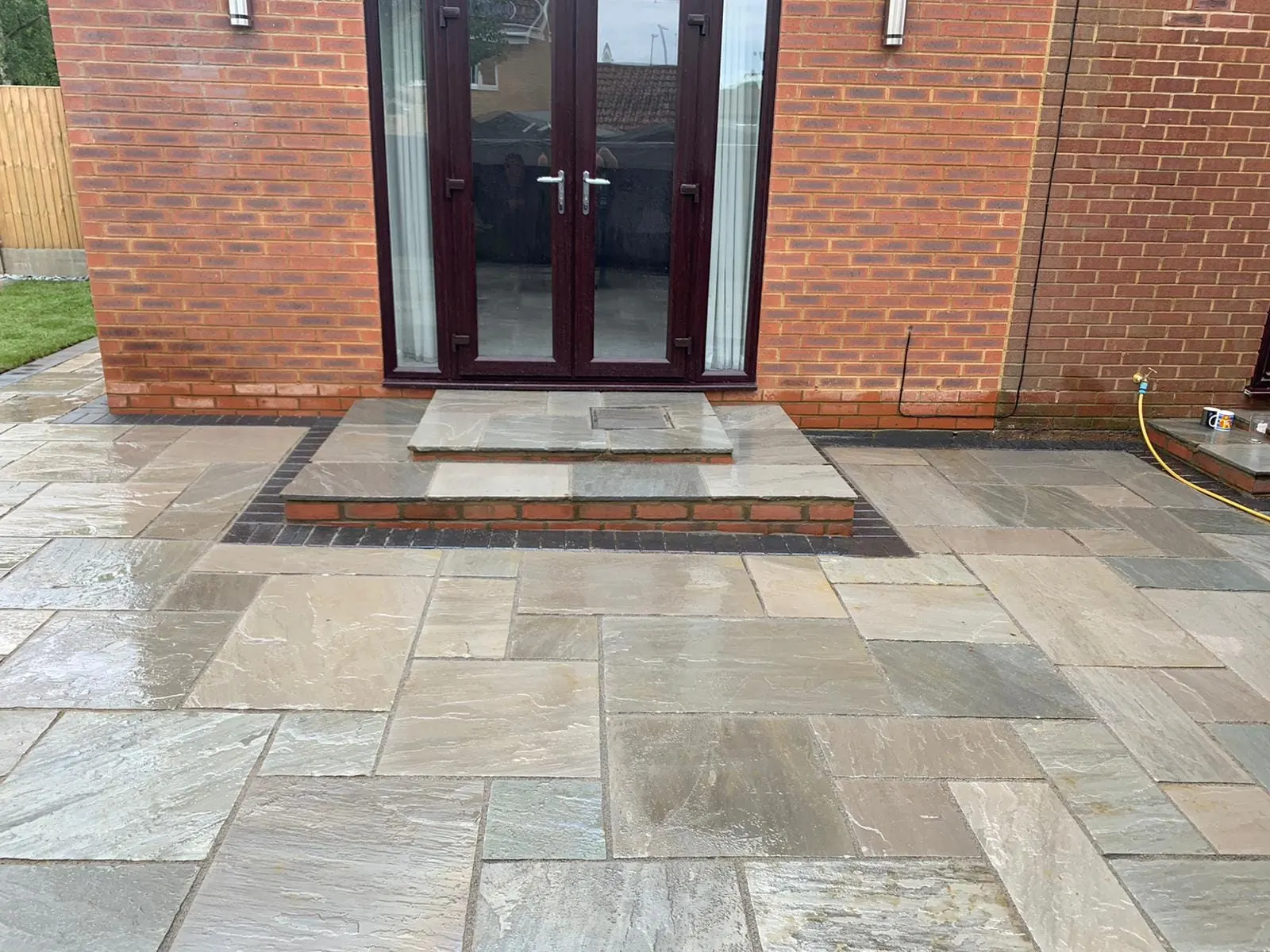 Grey sandstone patio with a step up to French doors