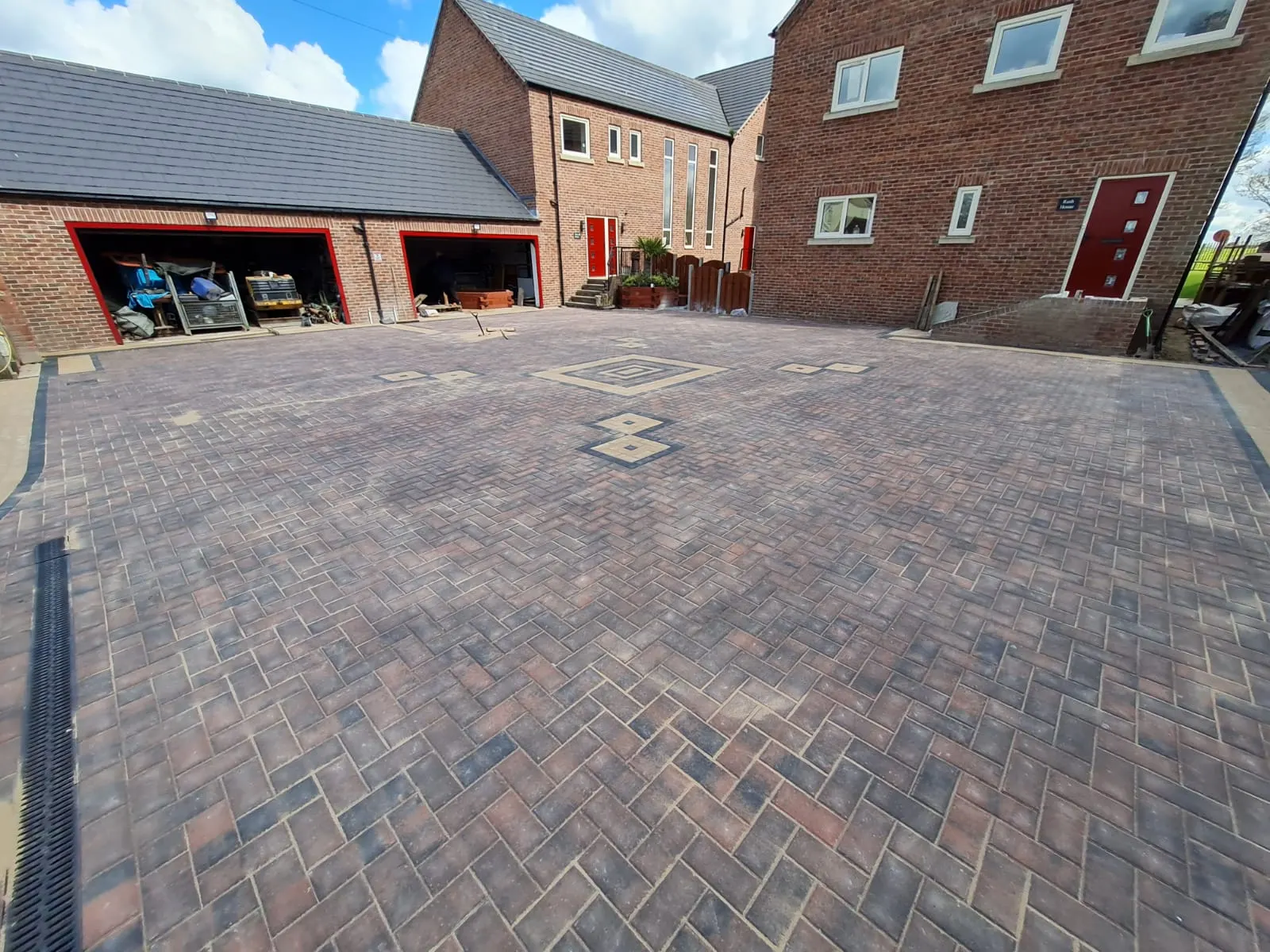 Large brindle block paving driveway with diamond features in front of new-build garages