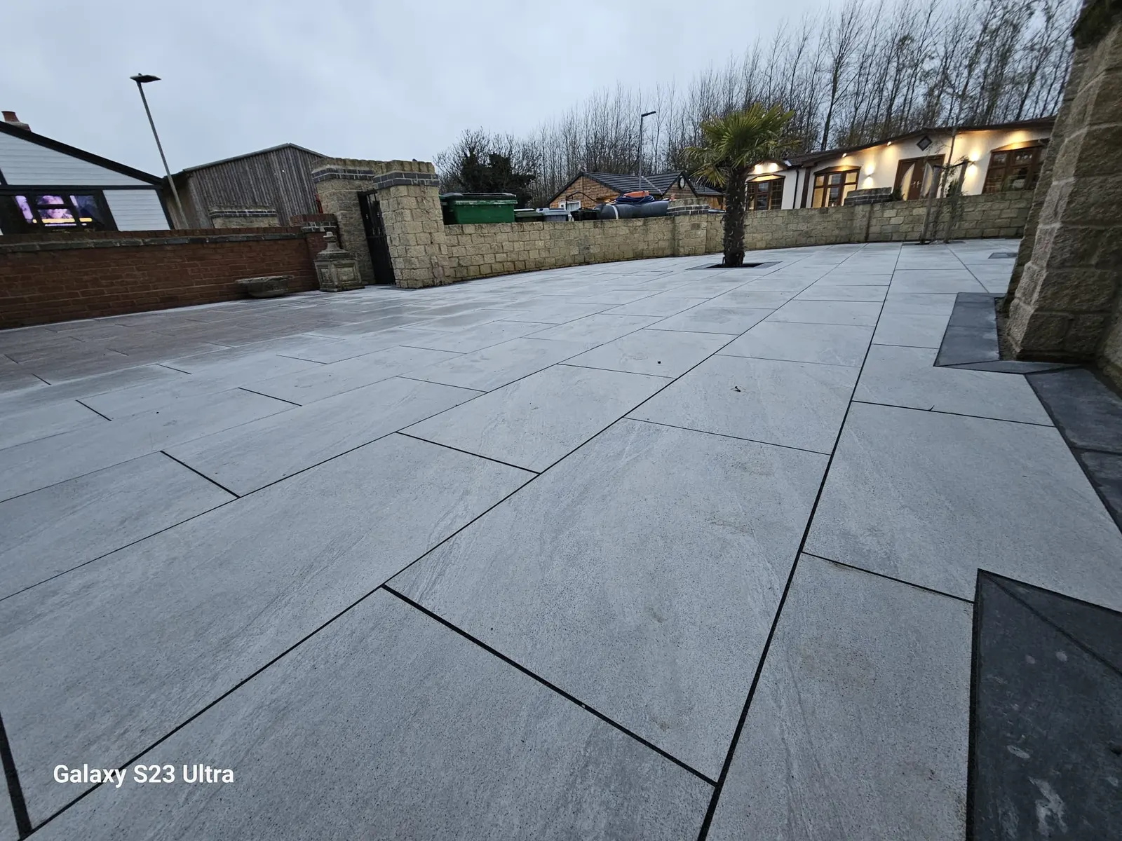 Large grey porcelain patio beside a detached bungalow