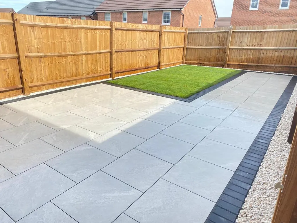 Light grey porcelain patio with a small lawn and a gravel edge