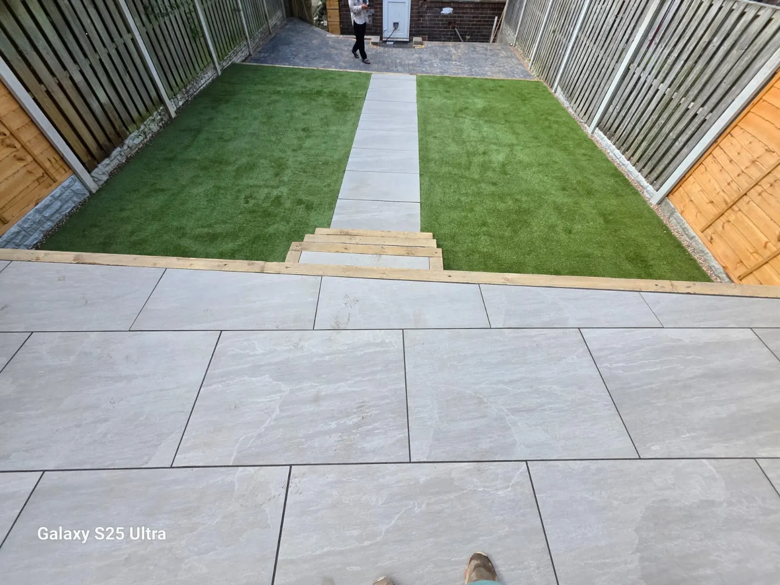 Light porcelain patio with artificial grass and a path beyond