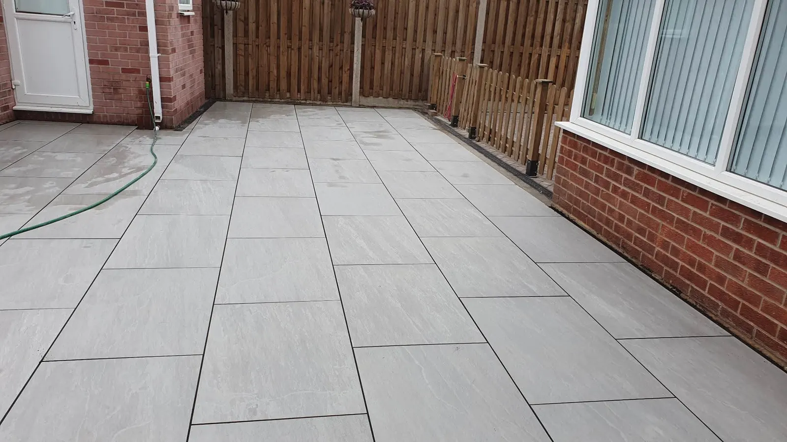 Light porcelain patio filling a fenced garden outside patio doors