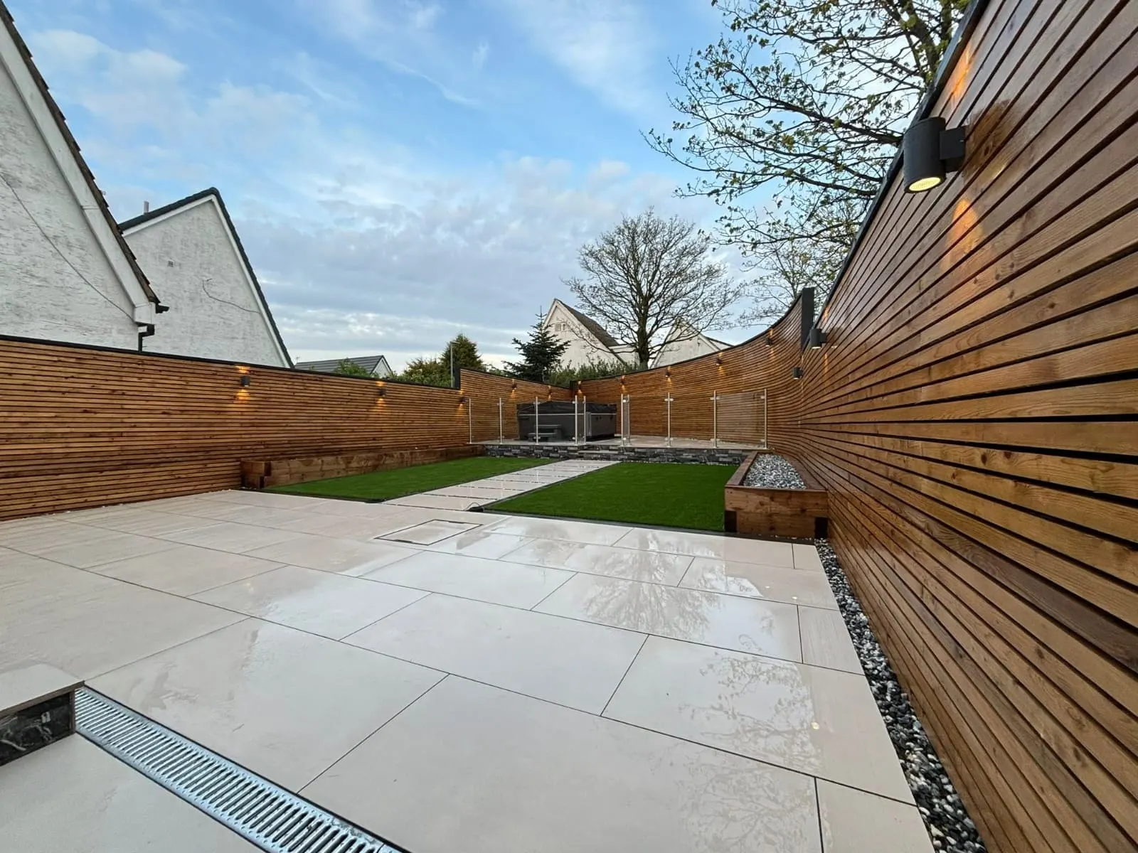 Light porcelain patio with a slatted fence and a channel drain