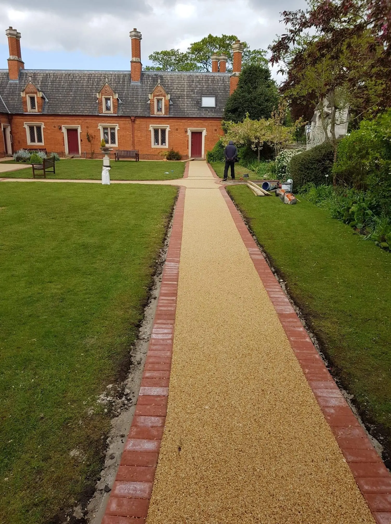 Long resin bound path with red block paving edging between two lawns