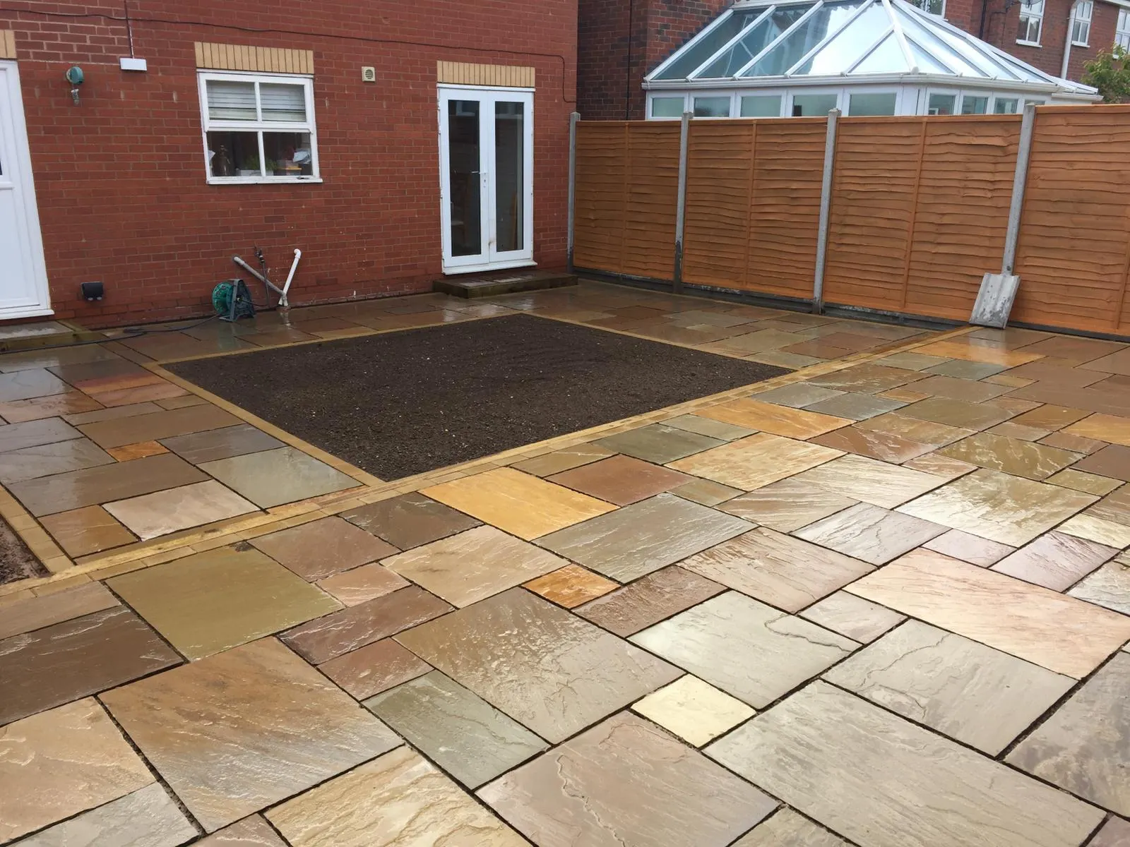 Sandstone patio with a planting bed near a conservatory