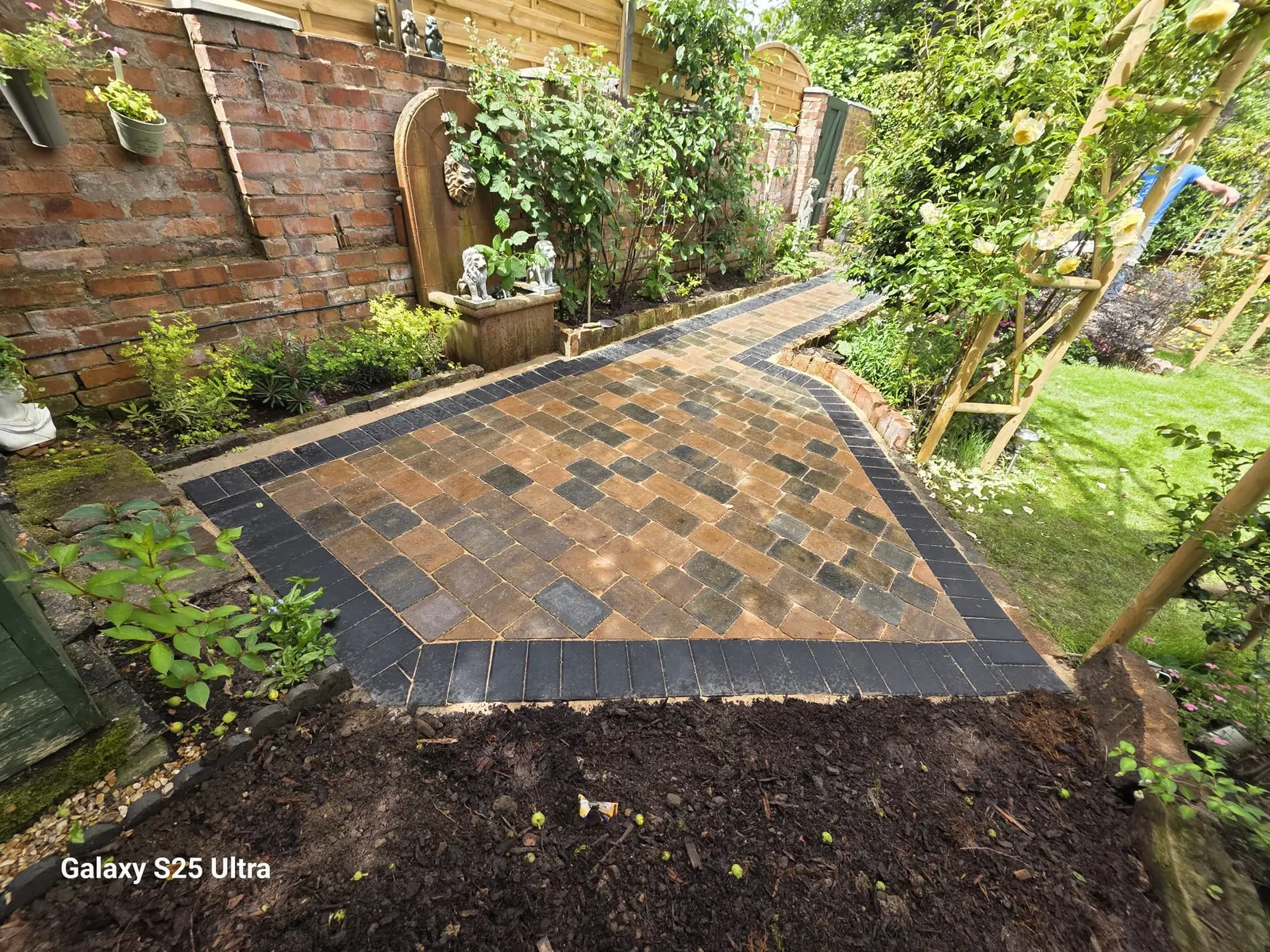 Multicolour block paving garden path with a charcoal border between planting
