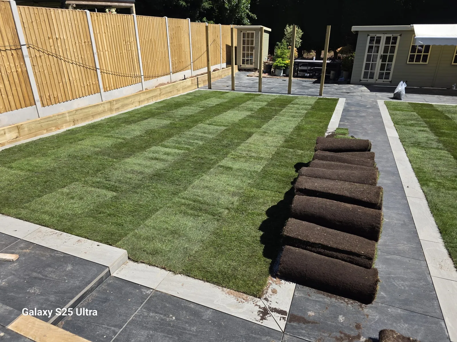 New turf being laid beside a grey porcelain path