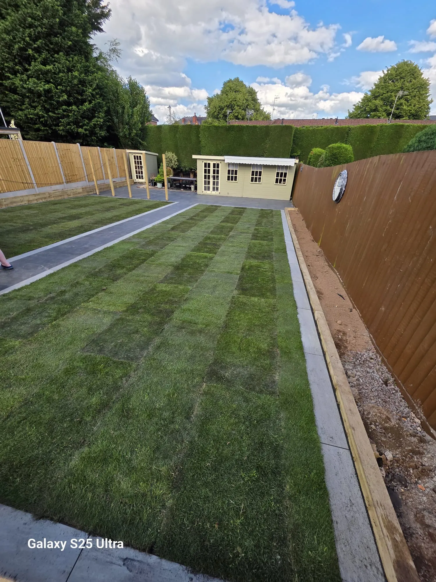 New turf lawn with a grey porcelain path along a fence