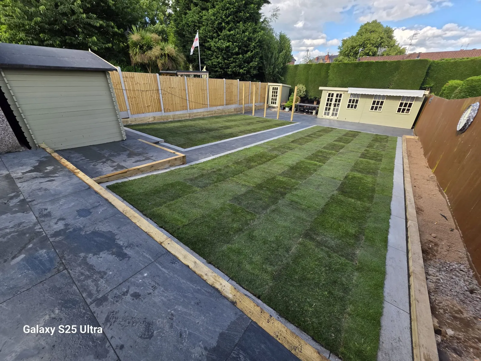 New turf lawn with timber edging leading to a garden room