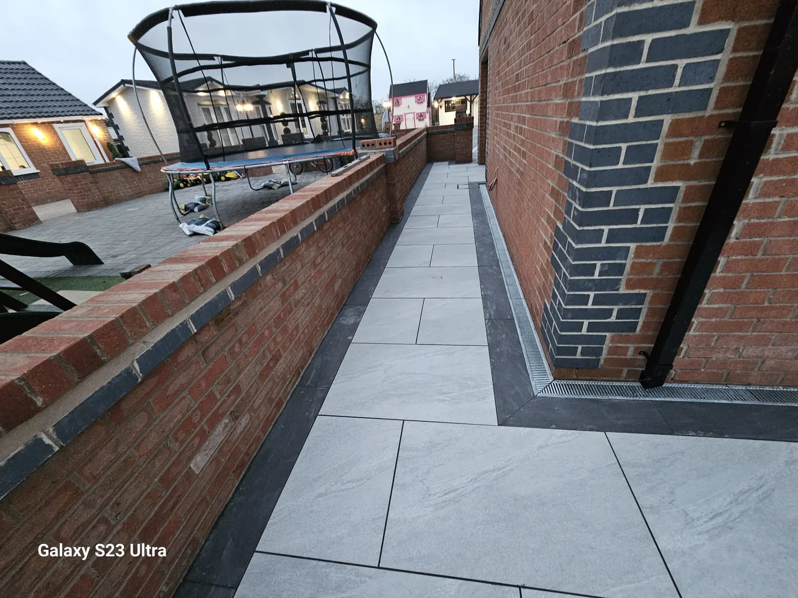 Porcelain path along a brick wall with a charcoal edge