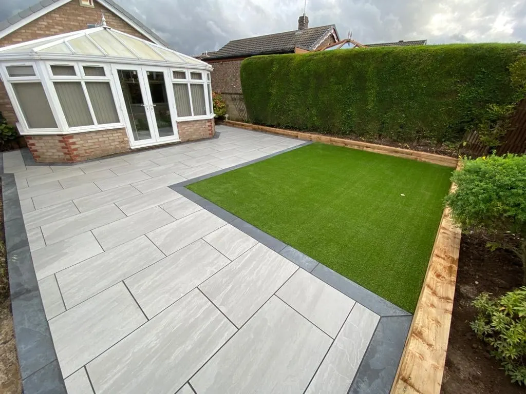 Porcelain patio and artificial grass by a conservatory