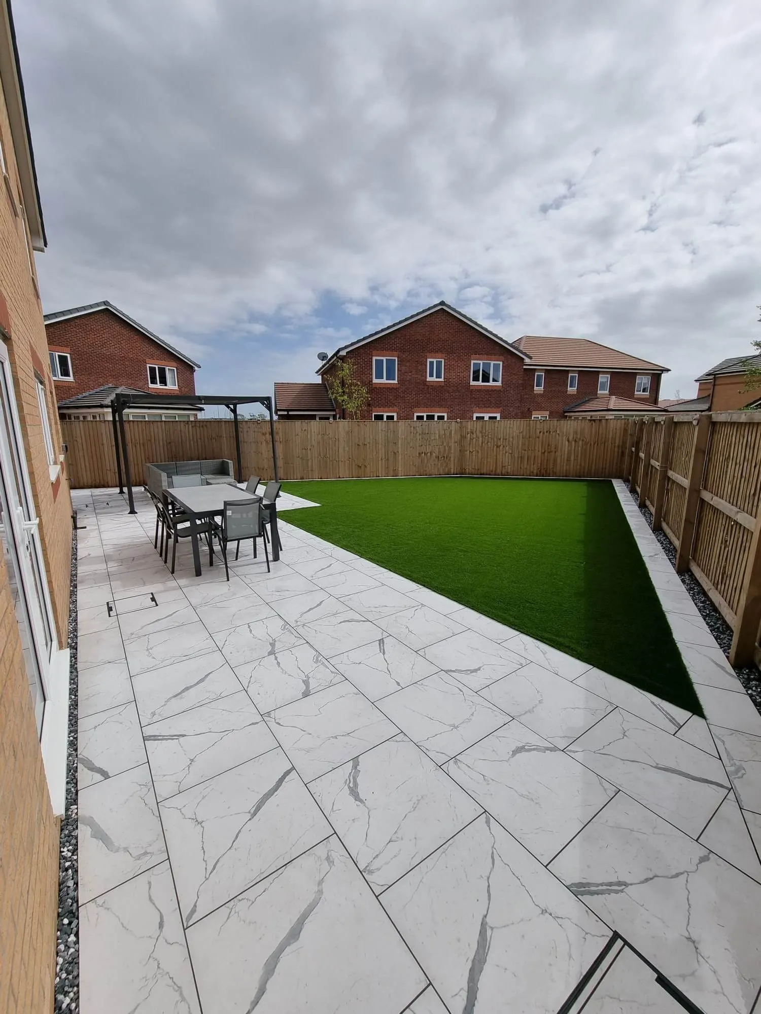 Porcelain patio with a dining area and artificial grass
