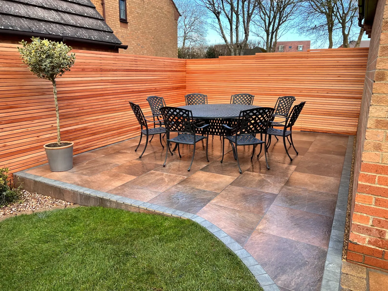 Porcelain patio with a dining set in front of a cedar slatted fence