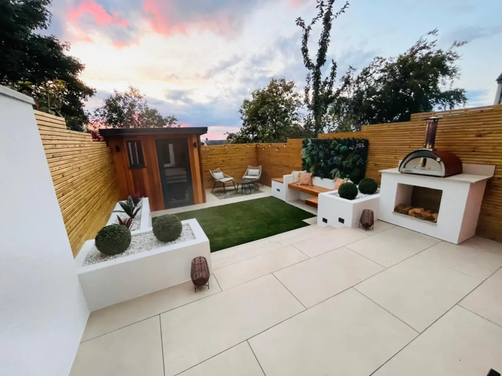 Porcelain patio with rendered planters, an outdoor kitchen and a pizza oven