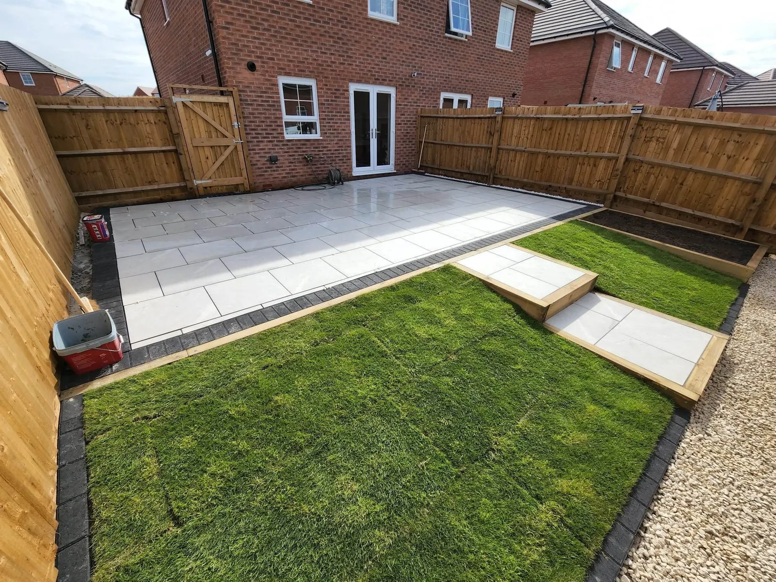 Porcelain patio and stepping slabs across a new lawn with a gravel border