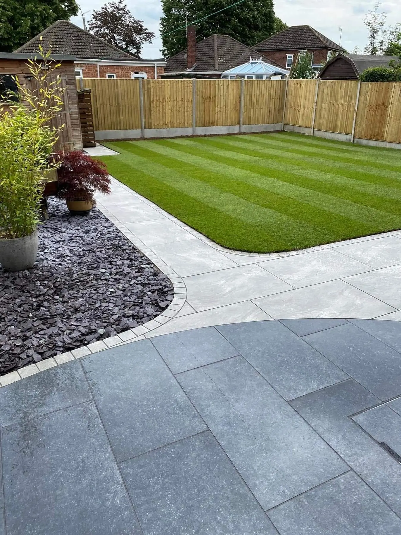 Grey porcelain patio beside a freshly striped lawn