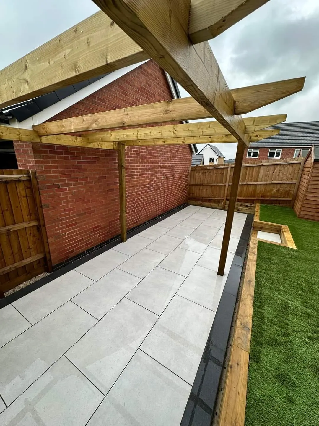 Porcelain patio under a timber pergola with a sleeper edge
