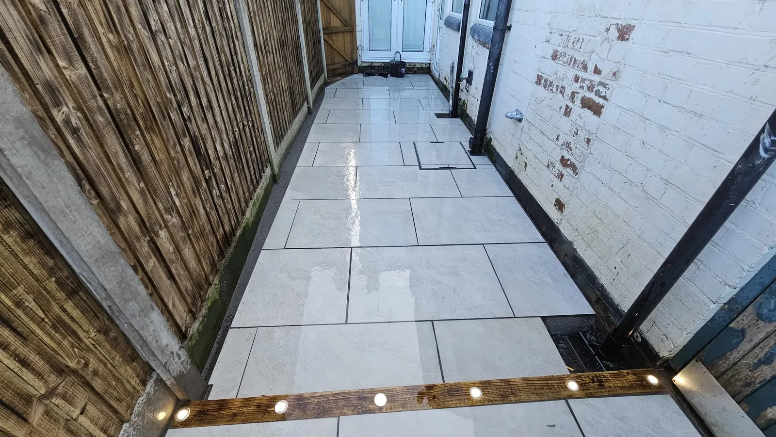 Narrow porcelain patio with a lit sleeper edge at dusk