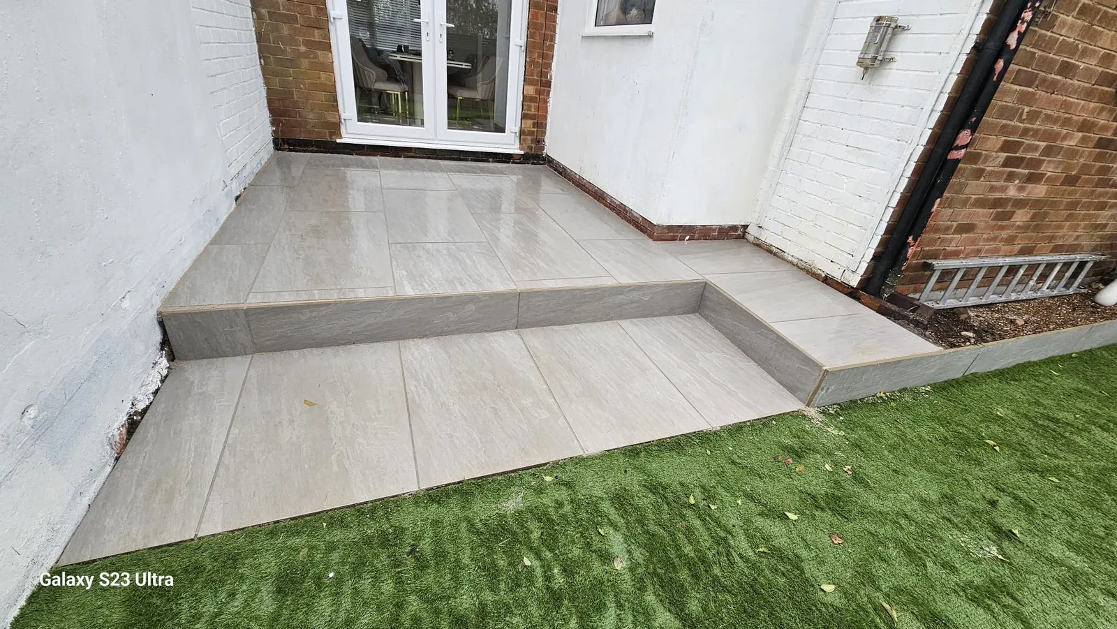 Porcelain patio with a step down to artificial grass