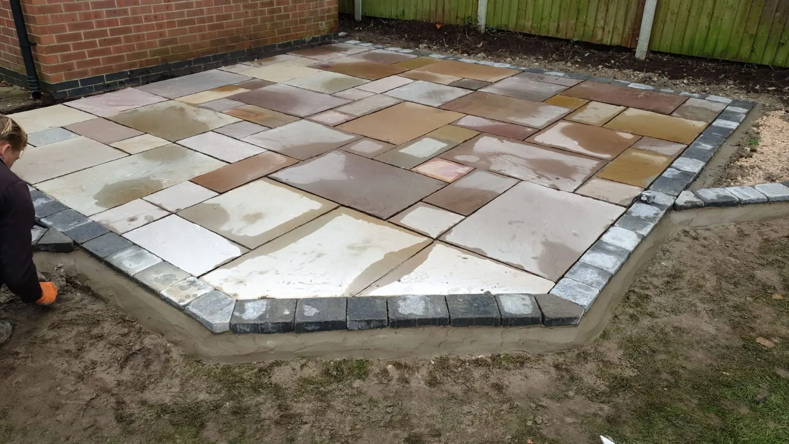 Rainbow sandstone patio with a charcoal border being laid