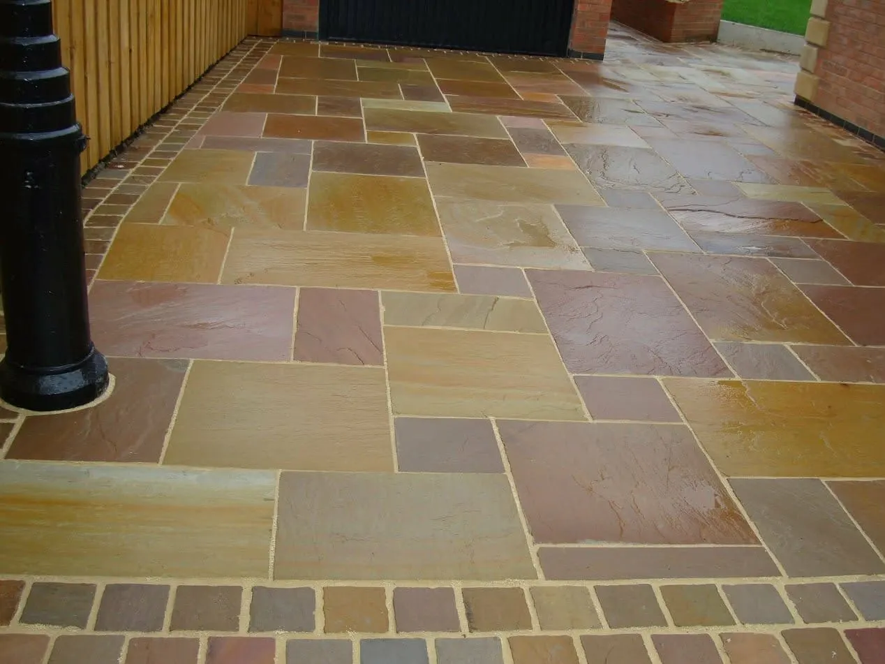 Rainbow sandstone patio with a red brick border