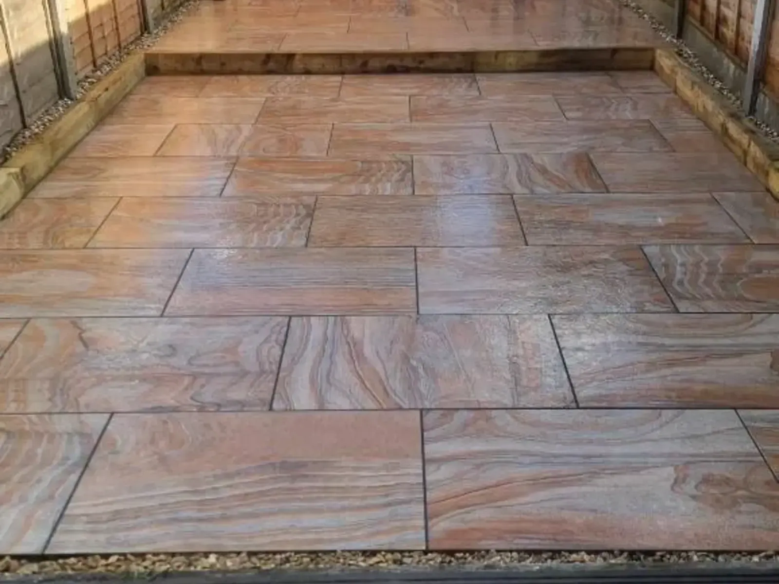 Pink-toned rainbow stone patio edged with sleepers