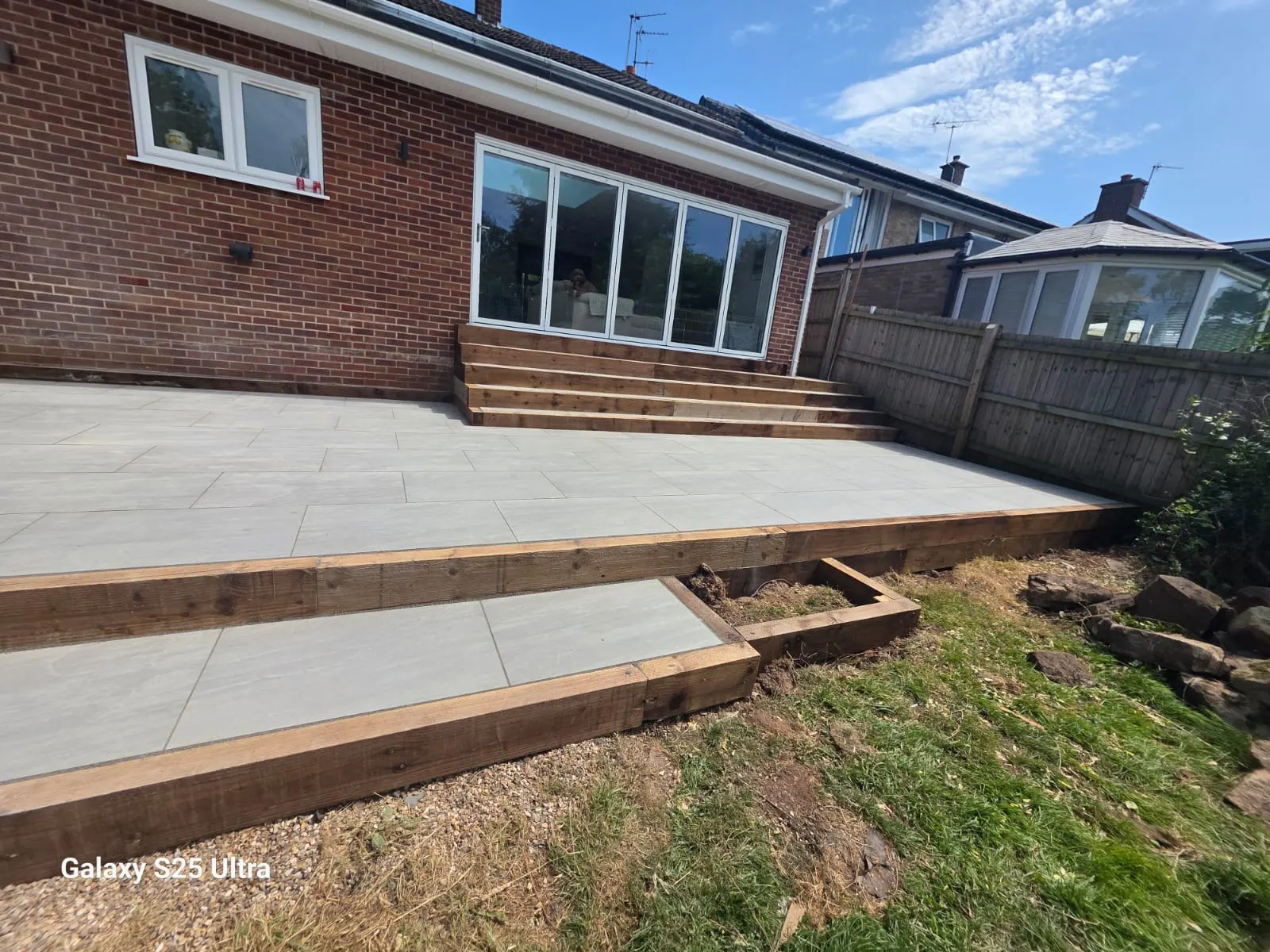 Raised grey porcelain patio with a sleeper edge and a lower step