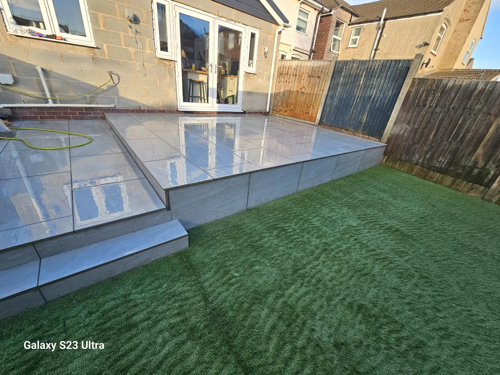 Raised porcelain patio with a step down to the lawn