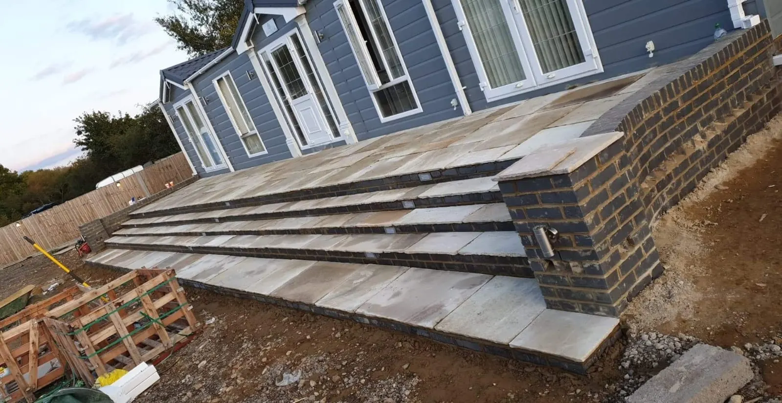 Raised porcelain patio with wide steps and a brick retaining wall