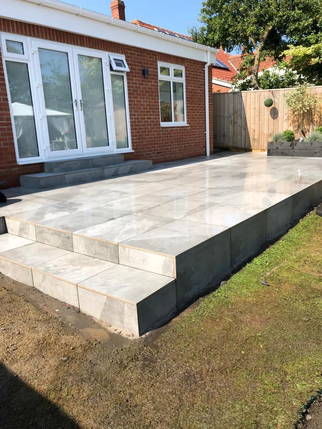 Raised porcelain patio with wide steps down to the garden