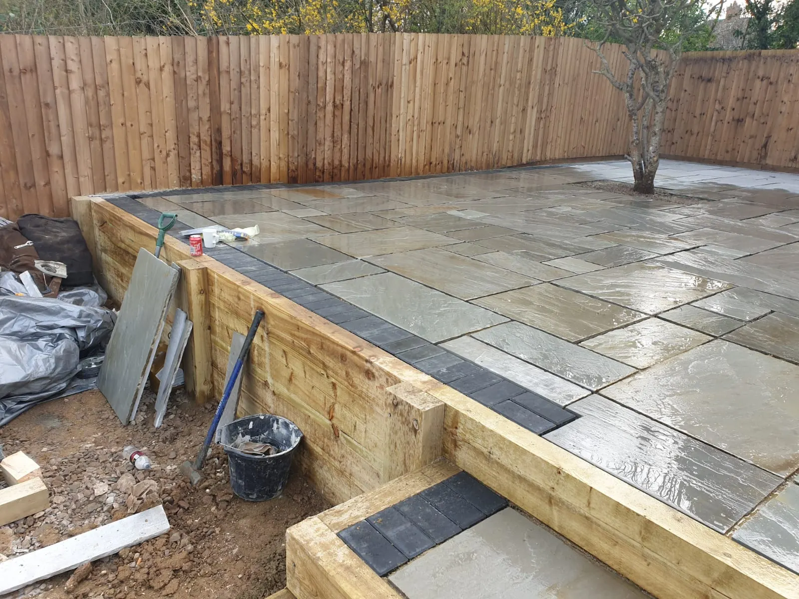 Raised sandstone patio on a sleeper retaining wall with steps