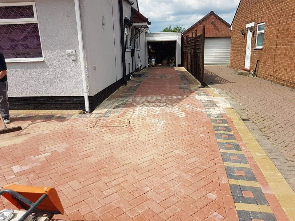 Red block paving driveway with patterned borders being finished