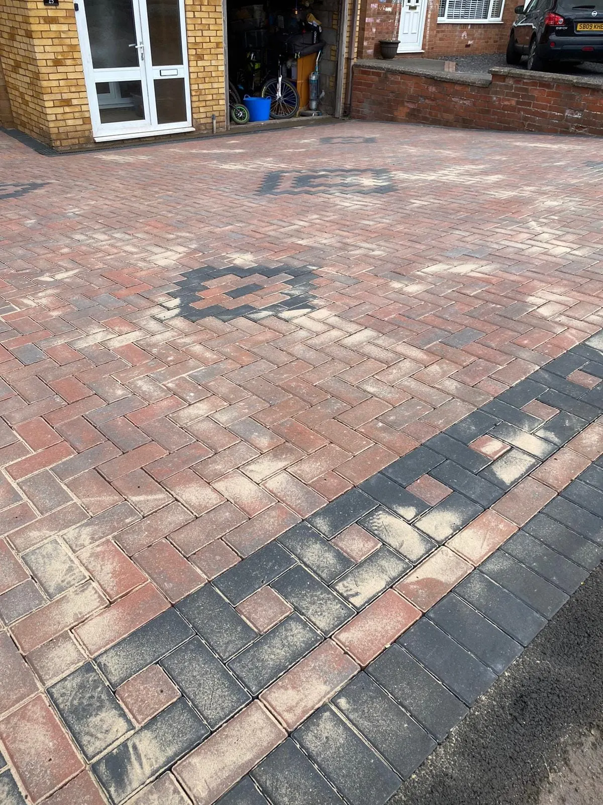 Red herringbone block paving driveway with a charcoal diamond and border