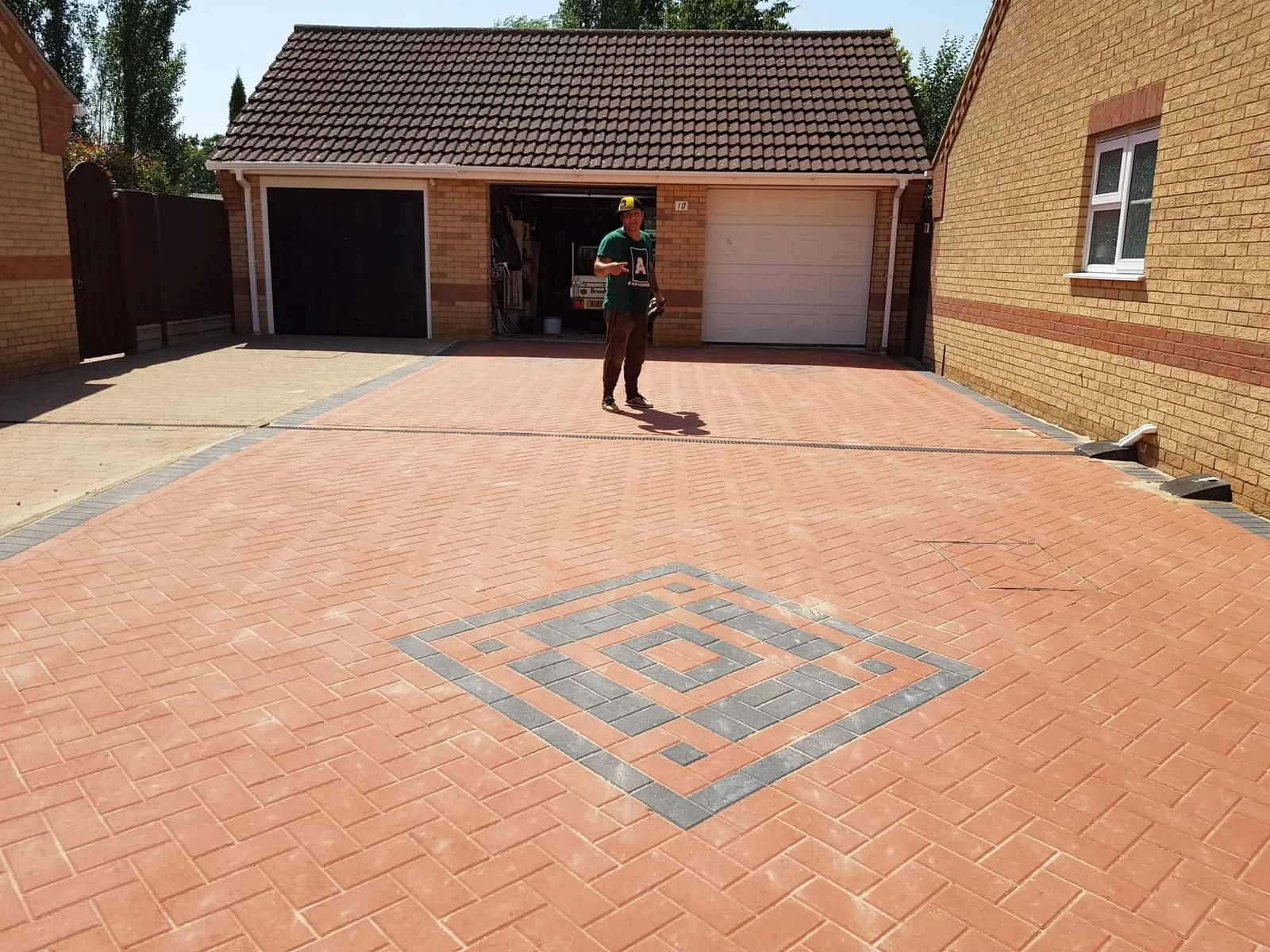 Red block paving driveway with a charcoal diamond feature in front of a double garage