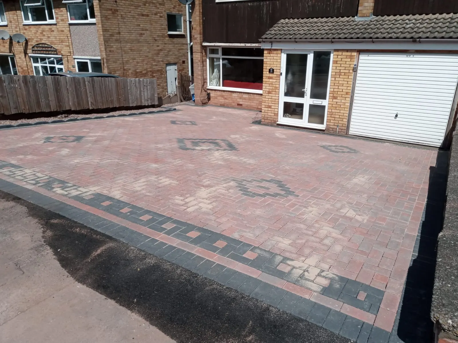 Red block paving driveway with a charcoal patterned border and diamond inserts