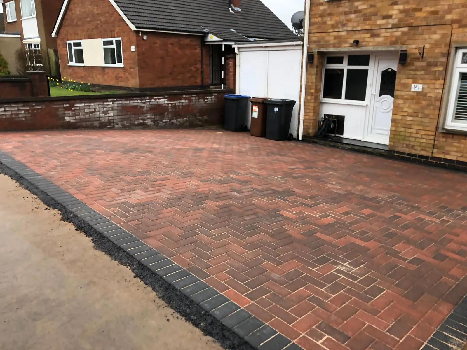 Red block paving driveway in herringbone with a charcoal kerb