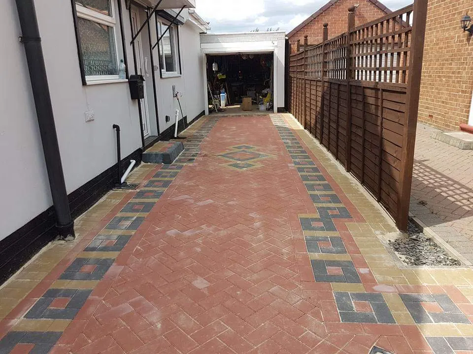 Long red block paving driveway with patterned borders up to a garage